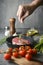 Hand sprinkle pepper for marinate meat in iron pan on the bottom on ingredients background. pouring shots, vertical image