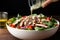 hand sprinkling pepper over a bowl of grilled chicken salad