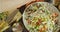 A hand sprinkling salt onto a salad seen from above