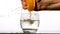 Hand squeezing juice of orange into glass of water