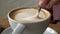 Hand Stirring Cappuccino in a White ceramic Cup on Wooden Tabletop