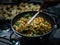 Hand stirring Indian chickpea and spinach curry in wok on gas stove indoors
