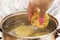 Hand stirring noodles boiling in a pot on top of a stove. Horizontally framed photo