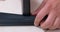 Hand stretches rubber fabric wooden board construction stapler, fixes staples.