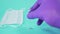 Hand in surgical gloves puts a glass ampoule with a vaccine on a blue surface