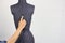 Hand of tailor gently change width of the back on a female sewing mannequin, gray background, copy space