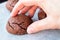 Hand takes baked cracked round chocolate cookie from a baking sheet with parchment paper. Tea or coffee snack