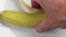 Hand takes yellow banana peel from white ceramic plate