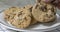 Hand taking a chocolate chip cookie from a plate of cookies