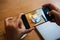 Hand taking a picture of hot latte art coffee cup with art foam on wooden table with her smart phone sitting at a coffee shop snap