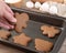 Hand taking traditional christmas gingerbread cookies from baking tray with ingredients