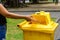 Hand throwing bottle in the yellow litter Bin