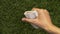 Hand throwing used paper cap on green grass at park, littering problem concept