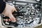 Hand with tool against the background of an automatic transmission with shallow depth of field