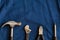 Hand tools such as hammers, pliers and screwdrivers are arranged on a blue denim background