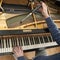 Hand and tools of tuner working on grand piano