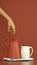 Hand touching clay jug on striped kitchen towel. Organic earthy warm brown colors. Vertical tie banner for social media