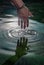 Hand touching the water of the lake, verifying the temperature of the water, the drops of water run down the fingers of the subjec