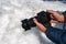 hand of traveler photographer with a modern DSLR camera photographing snow in winter in nature