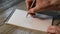 Hand tremor test in a patient with Parkinson`s disease. A man`s hand with a pen draws a spiral on a piece of paper close-up.