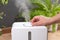 Hand turn on aroma oil diffuser at home  steam from the air humidifier  free space. Ultrasonic technology  increase in air