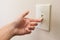 Hand turning wall light switch off.