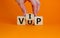 Hand turns a cube and changes the acronym `VUP` - very unimportant person to `VIP` - very important person. Beautiful orange