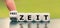 Hand turns a dice and changes the German expression `keine Zeit` `no time` in English to `Freizeit` `leisure time` in E