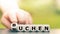 Hand turns a dice and changes the German word `suchen` `search` in English to `buchen` booking` in English.