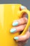 Hand with turquoise, mint blue nails with yellow cup