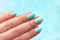 Hand with turquoise nails on blue background