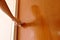 Hand twisting silver knob to opened wooden door in home