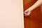 Hand twisting silver knob to opened wooden door in home