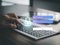 Hand typing keyboard showing login screen with password authentication on office table. Security of personal information.