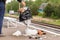 Hand of unknown man throws trash into overcrowded trash basket on a railway platform. Garbage bin