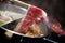 Hand using chopsticks pick premium raw beef sliced beef over the hot pot soup for Shabu Shabu