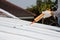 hand using glue gun or caulking gun on the roof.