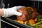 hand using oven mitt to remove beef roast from oven