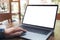 Hand using and touching laptop with blank white desktop screen on wooden table in cafe