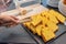 Hand using wooden tongs picking golden sandwich slice in restaurant