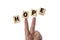 A hand with a victory gesture and wooden blocks with text 'HOPE