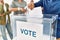 Hand of voter man putting vote in voting box at electoral center