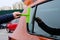 Hand washing orange car window with mop. Close up. Cleaning windscreen or windshield while car wash