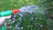 Hand with water hose nozzle tool watering flower bed in garden yard. Handheld. 4K