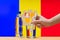 A hand with a water tester makes a measurement in a glass of clear water against the background of the flag of Andorra.