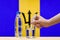 A hand with a water tester makes a measurement in a glass of clear water against the background of the flag of Barbados.