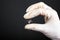 Hand in a white disposable glove holds a piercing tunnel on a dark background ear jewelry close-up