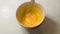 hand of a white elderly woman whips the egg yolks in a ceramic bowl