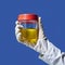 Hand in white glove holding transparent container with yellow liquid and red lid