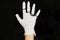Hand in white medical glove with modern rings on fingers on black background. Fashion and quarantine. Skin protection, prevention